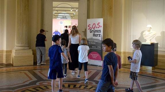 Kinder betreten eine Ausstellung