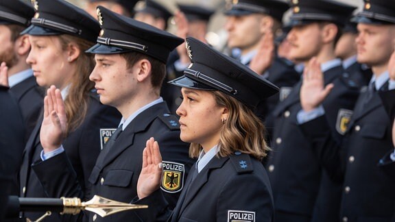Junge Bundespolizistinnen und Polizisten stehen bei ihrer Vereidigung im Innenhof der Bundespolizeiinspektion am Flughafen Frankfurt in Reih und Glied. 
