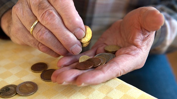 Ein Mann hält Münzen in den Händen