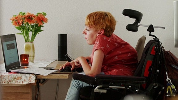 Eine Frau sitzt an einem Schreibtisch mit einem Laptop.