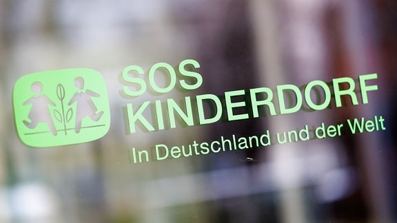 Der Schriftzug «SOS Kinderdorf - In Deutschland und der Welt» an einer Glasscheibe