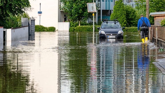 Ein Mann geht durch eine überflutete Straße.