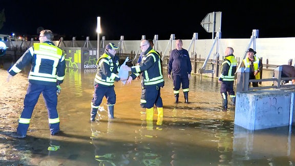 Mitglieder von THW und Feuerwehr stapeln Sandsäcke 