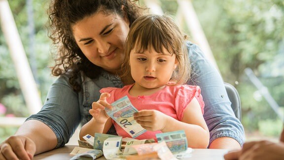 Ein kleines Mädchen hält Geldscheine in den Händen 