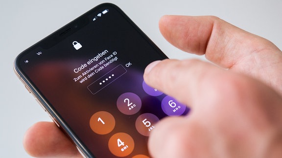 Ein Mann entsperrt 2018 ein iPhone mit einem Code.