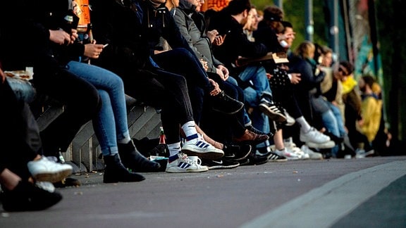 Viele Personen, größtenteils junge Leute, sitzen auf der Modersohnbrücke in Berlin 