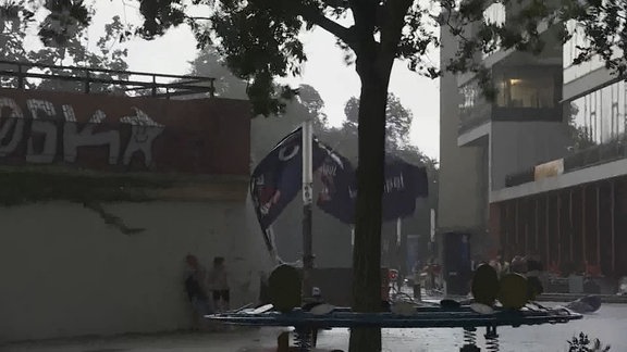 Ein großes Banner wird an der Moritzbastei in Leipzig vom Sturm mitgerissen.