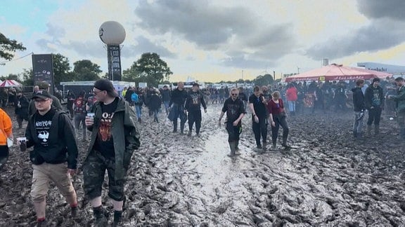 Festivalbesucher laufen über das schlammige Gelände in Wacken. 