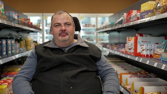 Ein Mann im Rollstuhl im Supermarkt.