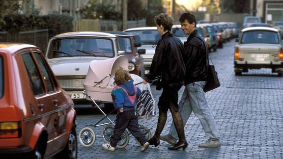 Eine junge Familie mit einem Kinderwagen überquert die Straße