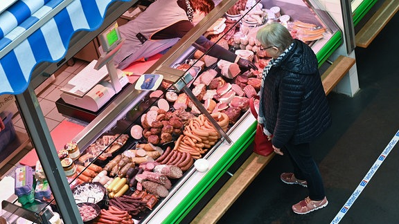 Eine Frau kauft in der Markthalle bei einem Fleischer ein.