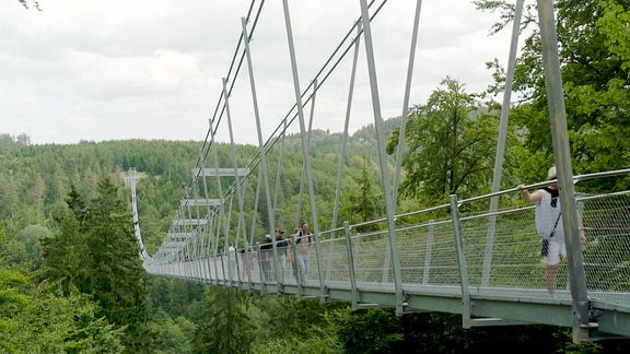 Menschen laufen über eine Hängebrücke.