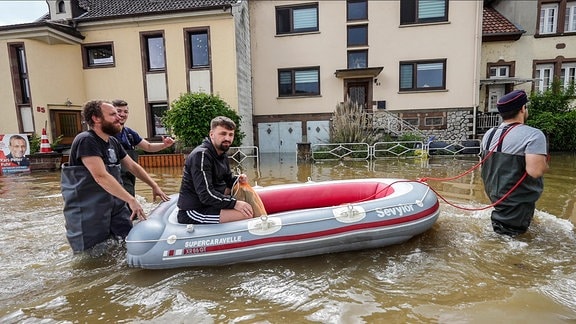 Einsatzkräfte der Freiwilligen Feuerwehr transportieren einen Mann mit einem Schlauchboot