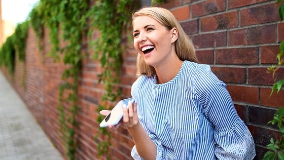 Lachende Frau mit Handy in der Hand