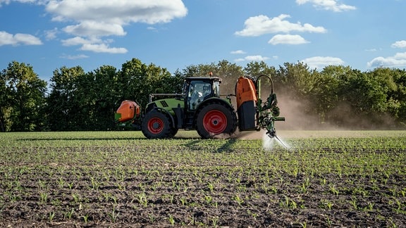 Moderner Traktor mit Feldspritze auf einem Maisfeld im Einsatz