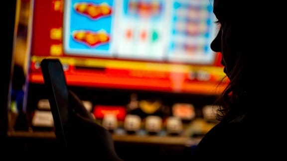 Sillhouette einer jungen Frau vor einem Glückspielautomaten