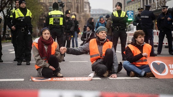 AktivistInnen der Letzten Generation blockieren die Straße am Stachus in München.