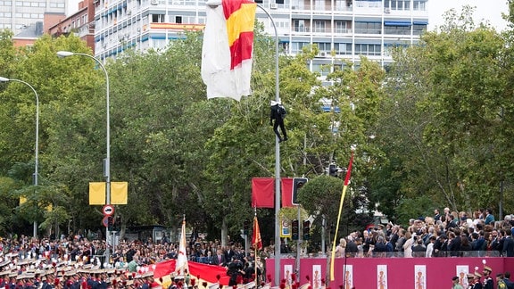 Fallschirmspringer hängt an Laternenmast während einer Militärparade.