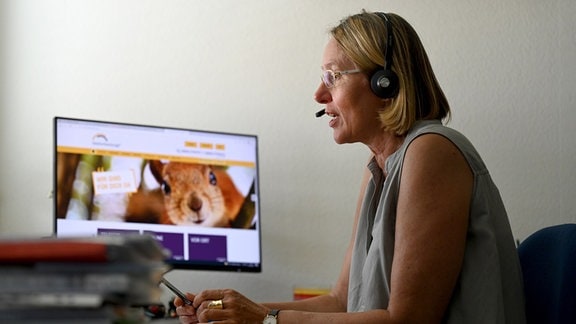 Martina Rudolph-Zeller, die Leiterin der Telefonseelsorge Stuttgart, sitzt mit einem Headset an ihrem Arbeitsplatz vor ihrem Rechner auf dem die Homepage der Telefonseelsorge angezeigt wird.