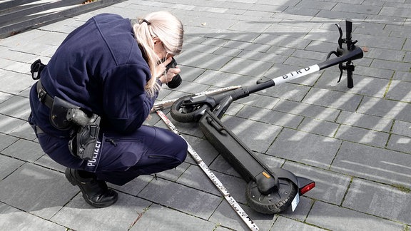 Polizistin fotografiert einen liegenden E-Roller