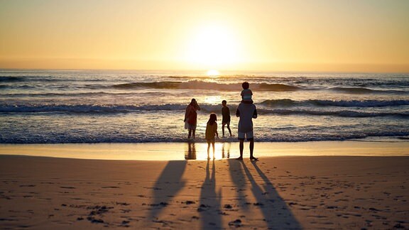 Familie bei Sonnenuntergang am Strand