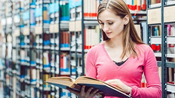 Eine Frau in einer Bibliothek blickt in ein Buch (Illustration).