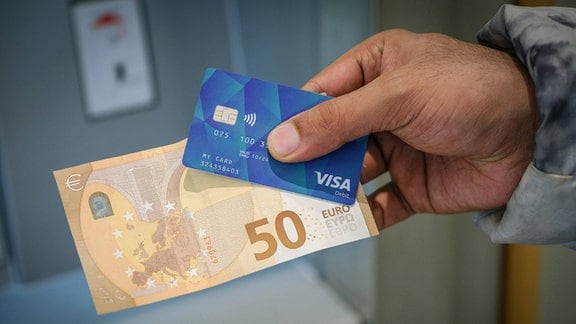 Eine Hand hält eine Geldkarte und einen 50-Euro-Schein.