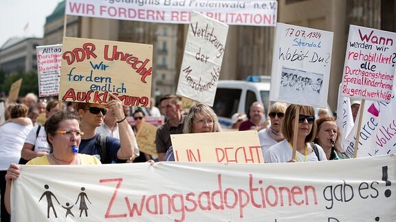 Teilnehmer einer Demonstration zum Thema Vergessene Opfergruppen des DDR-Regimes fordern Aufarbeitung stehen mit Plakaten am vor dem Brandenburger Tor in Berlin