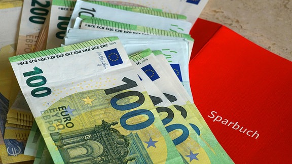 Euro-Banknoten liegen auf einem Sparbuch