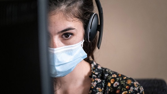 Frau arbeitet mit Mund-Nasen-Schutz am Computer