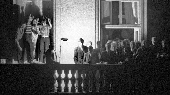 Der damalige Außenminister Hans-Dietrich Genscher (unter dem Fensterkreuz rechts) steht am 30.09.1989 mit anderen Politikern auf dem Balkon der bundesdeutschen Botschaft in Prag. 