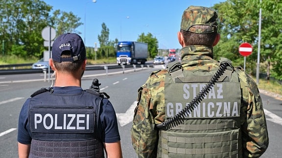 Ein deutscher Polizist und sein polnischer Kollegen stehen an einem Autobahngrenzübergang