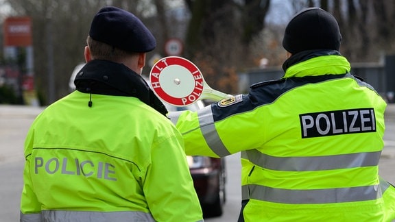 Ein Polizist aus Tschechien (l) und ein Bundespolizist winken nahe dem Dreiländereck von Deutschland, Polen und Tschechien ein Auto zu Kontrolle heraus. 