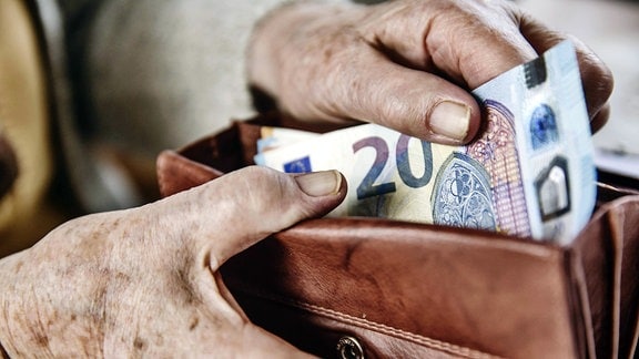 Seniorin zieht einen 20 Euro Schein aus ihrem Portemonnaie