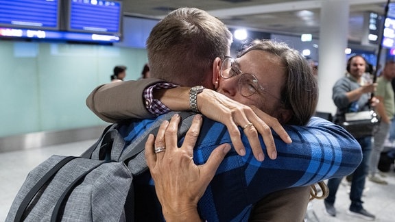 Angehörige und Freunde liegen sich nach der Landung eines Evakuierungsfluges am Flughafen Frankfurt in den Armen.