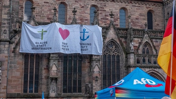 An einer Kirche hängen aus Anlass einer Demo für die AfD Banner für Glaube, Herz und Hoffnung statt Misstrauen, Hetze und Angst.