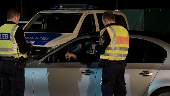 Zwei Bundespolizisten kontrollieren ein Fahrzeug