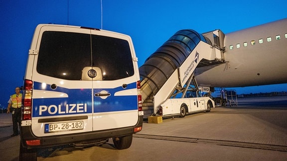 Ein Transporter der Bundespolizei steht auf dem Flughafen Leipzig-Halle vor einem Charterflugzeug. 