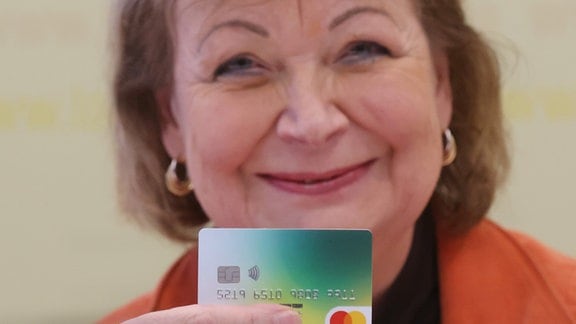 Martina  zeigt bei einer Pressekonferenz eine Bezahlkarte für Asylbewerber.