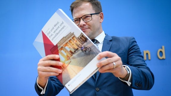 Carsten Schneider (SPD), Staatsminister für die neuen Bundesländer und Beauftragter der Bundesregierung für Ostdeutschland, präsentiert in der Bundespressekonferenz ein Dokument