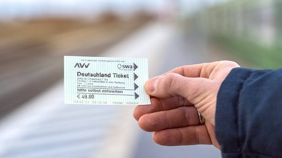 Ein Mann hält ein 49-Euro-Ticket in seiner Hand