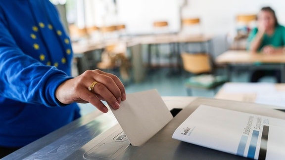 Eine Frau mit Europa-Hoodie wirft ihren Stimmzettel in die Urne.