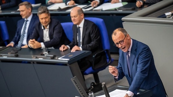 Friedrich Merz spricht vor Bundeskanzler Olaf Scholz, Robert Habeck und Christian Lindner während der Debatte nach einer Regierungserklärung zur Haushaltslage im Bundestag.