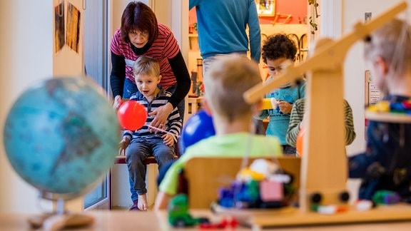 Kinder experimentieren 2018 in einer Kindertagesstätte mit Luftballons.