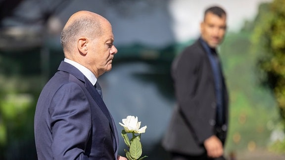 Bundeskanzler Olaf Scholz (SPD) legt eine Blume an einer Kirche in der Nähe des Tatorts in Solingen ab.