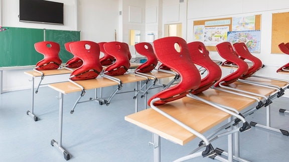 Leerer Klassenraum mit hochgestellten Stühlen.