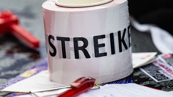 Eine Rolle Absperrband mit der Aufschrift "Streik" liegt beim bundesweiten Hochschulaktionstag auf einem Tisch am Fritz-Förster-Platz. 