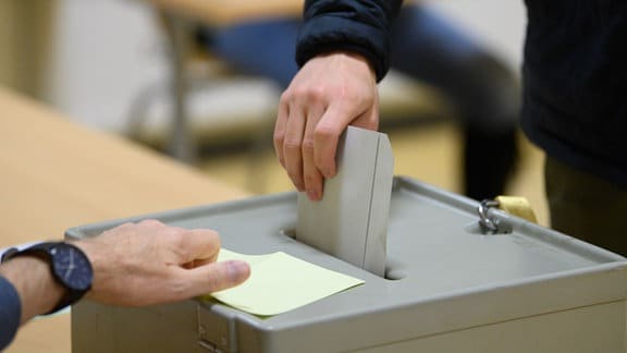 Ein Wähler wirft 2021 im Wahllokal seinen Stimmzettel in eine Wahlurne.