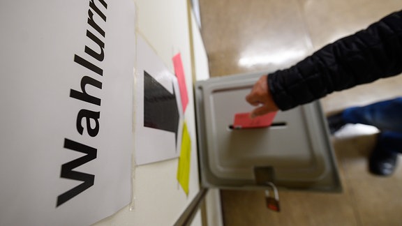Ein Mann wirft einen Wahlbrief für die Europawahl in eine Wahlurne.