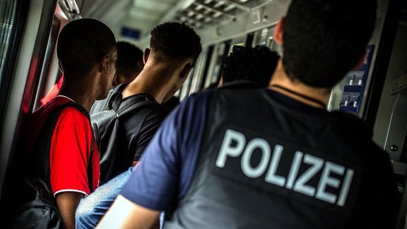 Ein Bundespolizist geleitet am 09.09.2014 im stehenden Eurocity in Rosenheim (Bayern) zahlreiche Flüchtlinge in Richtung Ausgang.